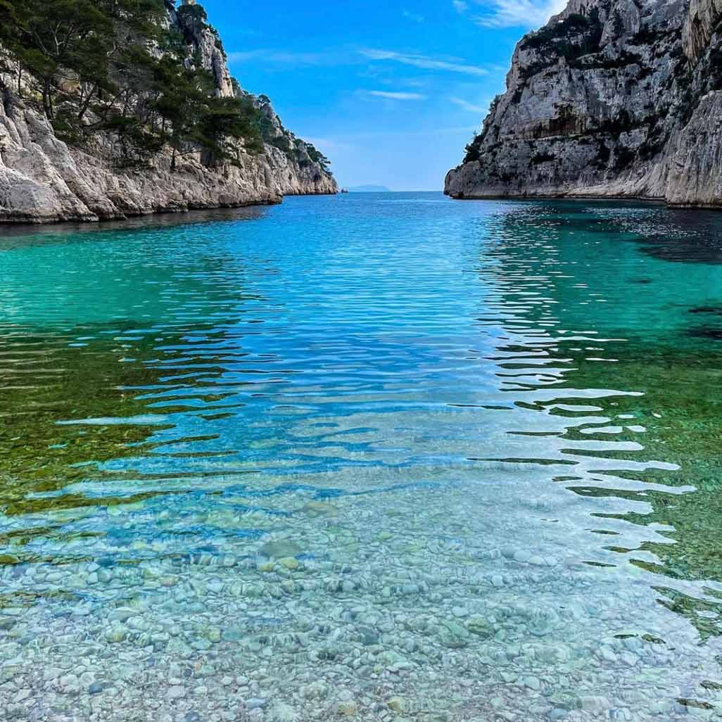 Crystal-clear water and white pebble seabed at the shore of the En-Vau calanque.