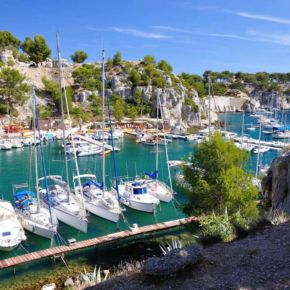 Numerous sailboats moored in the natural, winding harbor of the Port-Miou calanque.