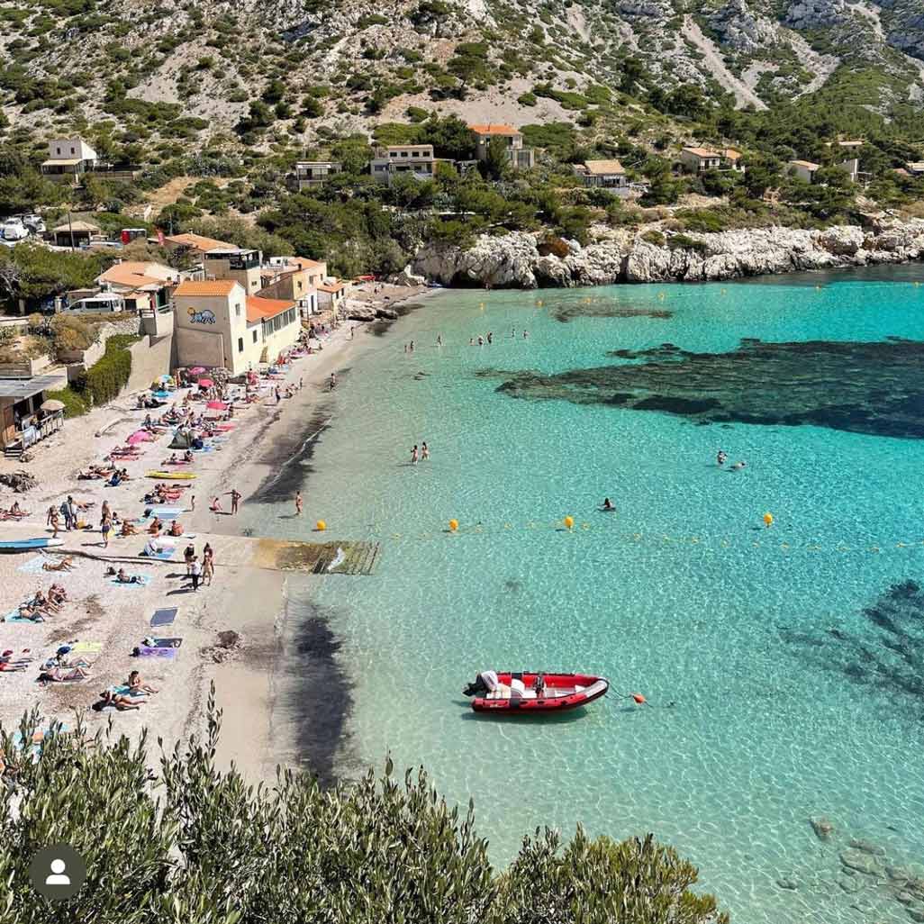 Busy Sormiou beach lined with traditional cottages and clear waters.