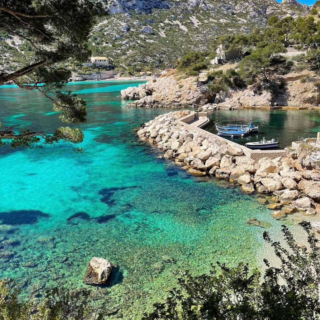 Small fishing harbor with turquoise waters and a stone pier in Sormiou.