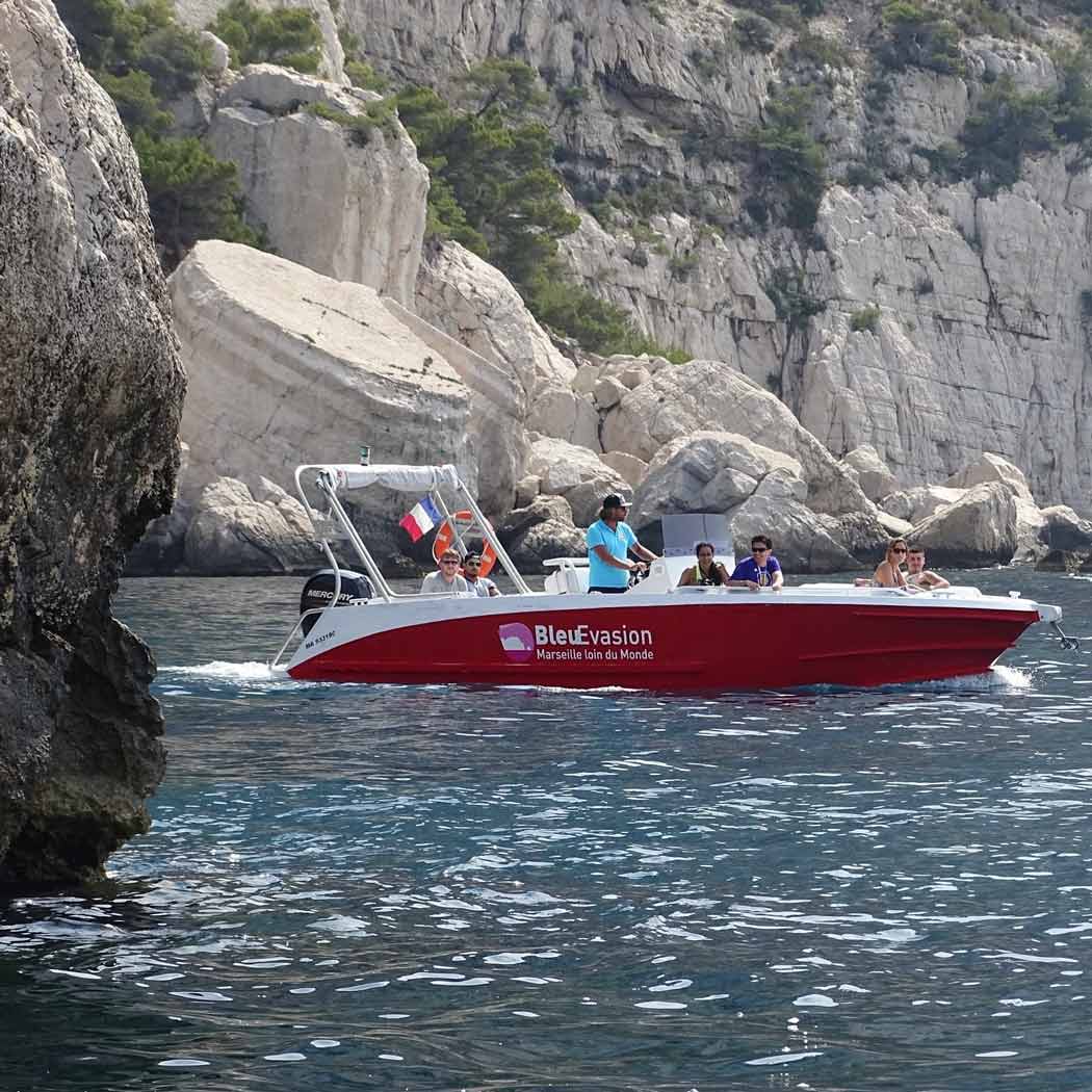 Bleu Évasion boat carrying passengers in front of the Sugiton cliffs.