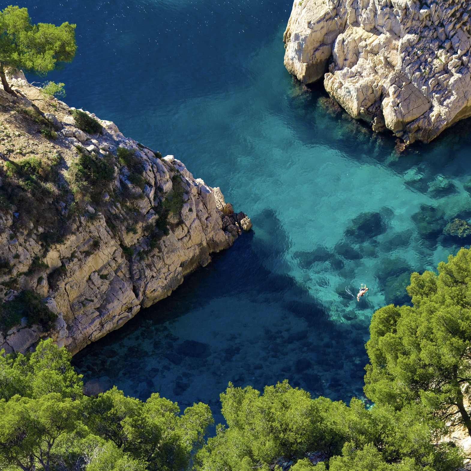 A swimmer in the turquoise waters at the base of Sugiton's cliffs.